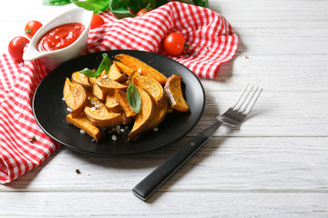 Plate with cooked sweet potato on wooden table