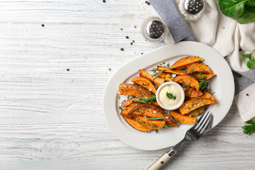 Plate with cooked sweet potato on wooden table