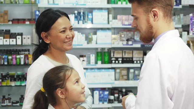 An apothecary came up to mother and daughter. They ask him questions about medicines. He advises them on something. Mom and daughter are in the pharmacy