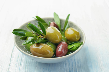 Bowl with canned olives on white wooden background