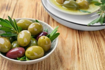 Bowl with canned olives on wooden background
