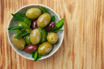 Bowl with canned olives on wooden background