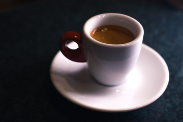 A cup of coffee is americano on a dark background.