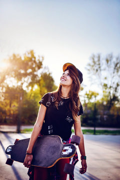 Cute urban girl holding skateboard in skatepark - hipster style photo