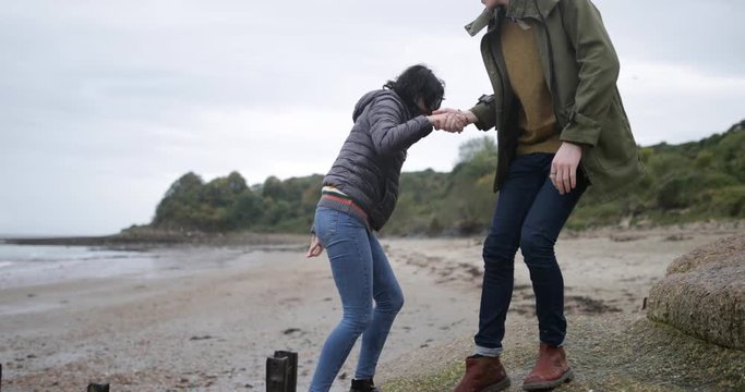 Boyfriend helping girlfriend climb a rock