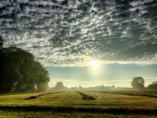 Fototapeta premium Colorful countryside sunrise over the agraric fields showing the dramatic colors and clouds in the sky