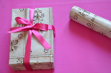 Craft paper wrapped present box craft rope bow ribbon on bright pink, crimson background, top view....