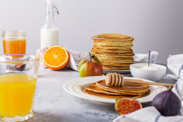 Pancakes with honey, fruit and coffee on a gray background