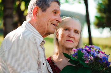 Happy and very old couple smiling in a park on a sunny day