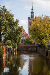 Obraz premium View of an idyllic canal, Love Bridge and church on a sunny day in Gdansk, Poland, at autumn.