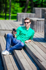 Fototapeta premium Young guy with smartphone outdoors in the park Man using mobile smartphone.