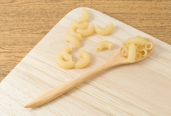 Elbow Macaroni or Gomiti Pasta on Wooden Cutting Board