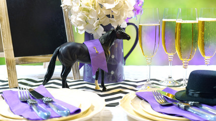 Horse racing Racing Day Luncheon fine dining table setting with small black fascinator hat, decorations and champagne.