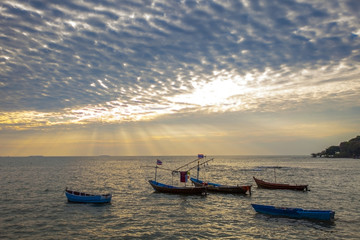 Fototapeta na wymiar domestic fishery boat on plain sea and dramatic of cloud and sun light sky