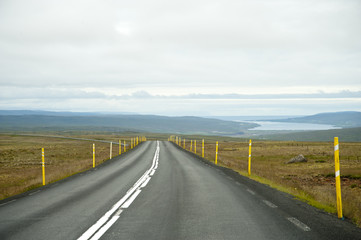 Road in a typical Icelandic landscape, a wild nature of rocks and shrubs, rivers and lakes.