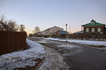 Typical cityscapes of Suzdal/City landscape of Suzdal. Low-rise wooden and brick buildings, The road is covered with asphalt. On the roadside lies the snow.Suzdal.Golden Ring of Russia