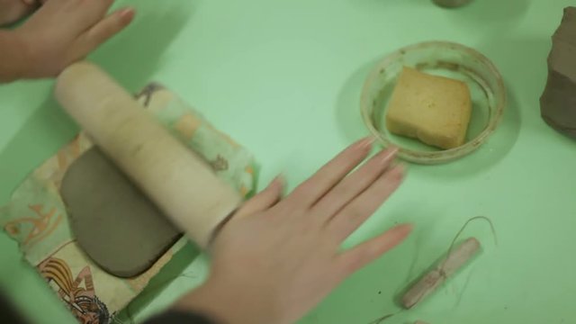 The master prepares clay for making a souvenir. Work process in an art workshop, work with clay. master unrolls the clay. body parts