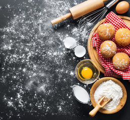 Baking ingredients. Bowl, eggs, flour, eggbeater, rolling pin and eggshells on black chalkboard from above.