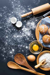 Baking ingredients. Bowl, eggs, flour, eggbeater, rolling pin and eggshells on black chalkboard from above.