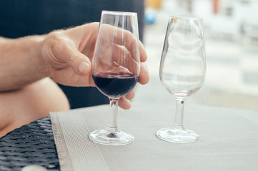 Close up on hand holding mobile smartphone and winetasting restaurant background. Modern internet connection networking, texting online luxury lifestyle