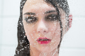 young sensual woman under shower splash of water looking at camera