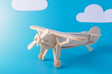 Wooden toy airplane on a background of blue sky with paper clouds. Concept travel and airlines