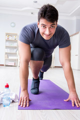 Young man exercising at home in sports and healthy lifestyle con