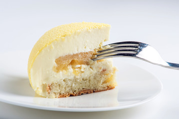 A piece of yellow cake filled with white souffle, biscuit and pineapple. Concept design desserts
