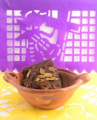 Mexican traditional pumpkin sweet made with piloncillo and cinammon on a clay pot, known as calabaza en tacha with ornamental papel picado
