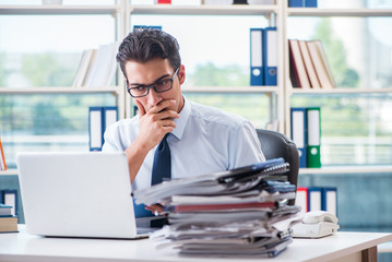 Businessman with excessive work paperwork working in office