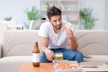 Man eating pizza having a takeaway at home relaxing resting