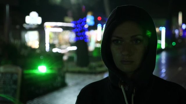 Silhouette of a man in a hood standing on a night street. 4k
