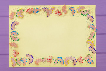 A frame made of colored pencil shavings a on a yellow paper