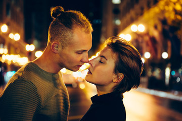 Beautiful young couple in love kissing on the night city street