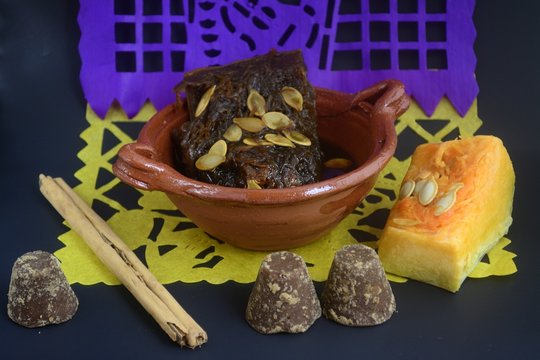 Mexican traditional pumpkin sweet made with piloncillo and cinammon on a clay pot, known as calabaza en tacha with ornamental papel picado