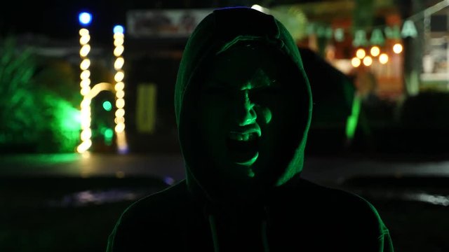 Silhouette of a man in a hood standing on a night street. 4k