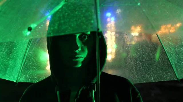 Silhouette of a man in a hood standing on a night street. 4k