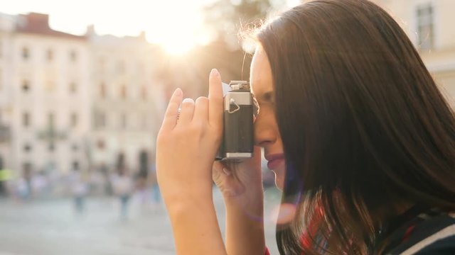 Beautiful young brunette woman taking photos of beautiful old buildings while traveling around the city on the sunny day. Close up. Side shot