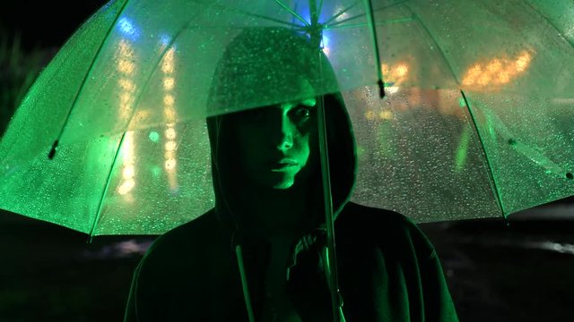Silhouette of a man in a hood standing on a night street. 4k