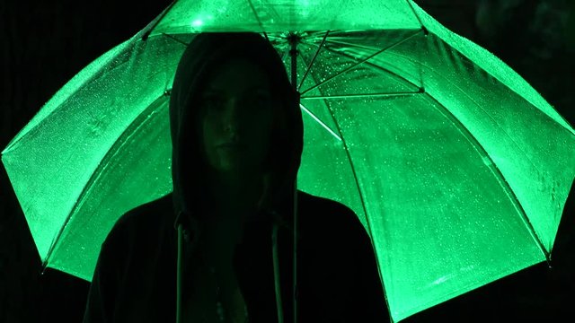 Silhouette of a man in a hood standing on a night street. 4k