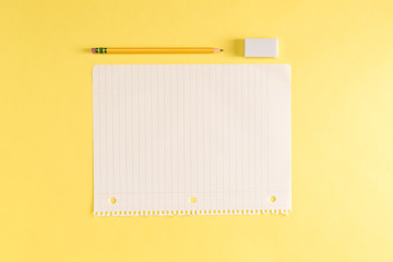 Pencil and blank sheet of notebook paper on a yellow background