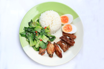 stir fried vegetables, Hard-boiled egg, Fried pork and Fried chicken wings with thai jasmine rice on dish. Thai food.
