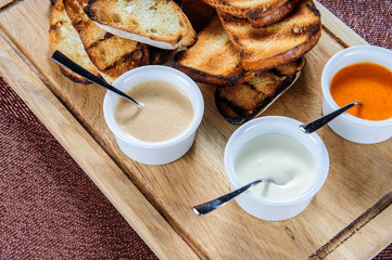 Slice of toast roasted in breaded with cheese and sesame slipped in a sauce on a wooden board