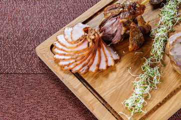 Baked goose leg in berry sauce on a wooden plate .