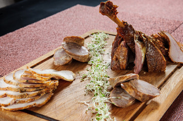 Baked goose leg in berry sauce on a wooden plate .