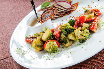 Slised meat meal with vegetables on white plate