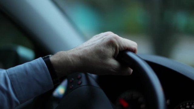 Closeup of person hands on steering wheel driving car. Man driving a vehicle. Slow-motion 120fps driving commuting from work