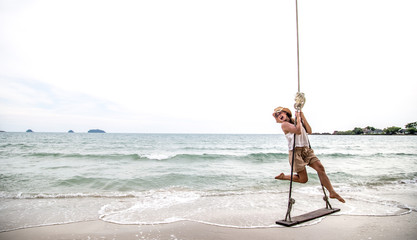 girl stands on a swing on the beach of Thailand
