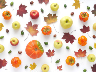Autumn concept. Pumpkin, autumn leaves, persimmon, red and green apples on a white background. Pattern of fresh vegetables. Top view, flat layout.