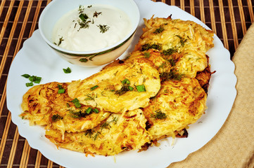 Fried potato pancakes with sour cream on old wooden background . Traditional Ukrainian cuisine